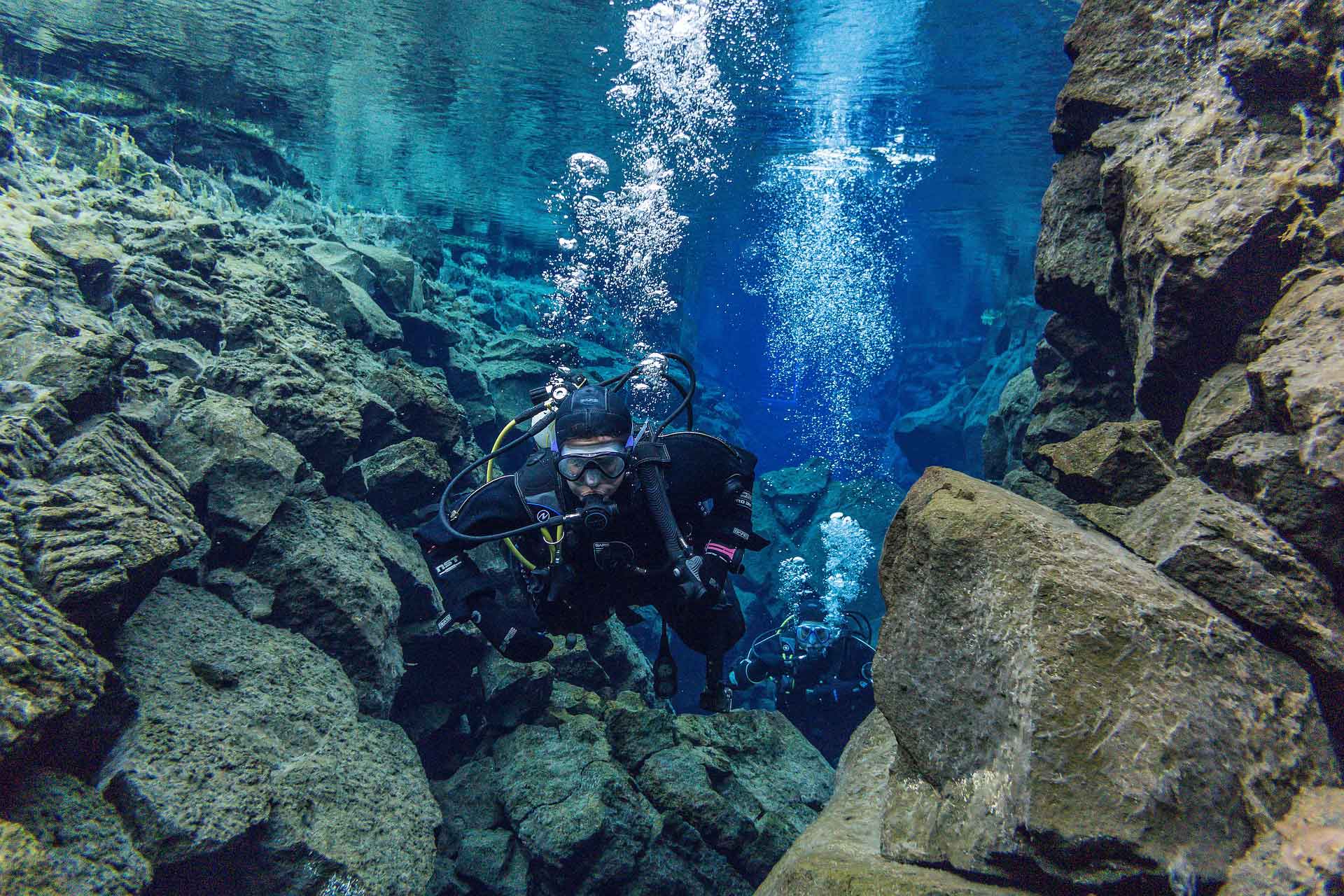 Scuba divers diving in Silfra crack in Iceland